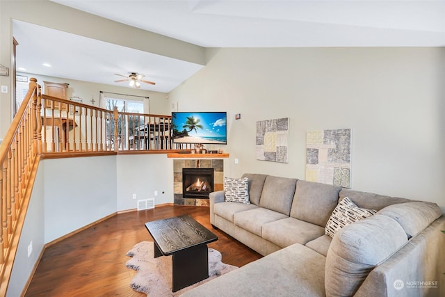 living room with ceiling fan, a tile fireplace, dark wood-type flooring, and lofted ceiling