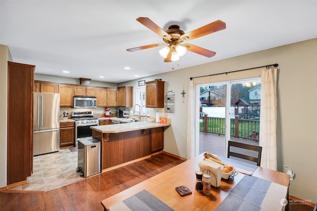 kitchen featuring a kitchen bar, light hardwood / wood-style floors, appliances with stainless steel finishes, sink, and kitchen peninsula