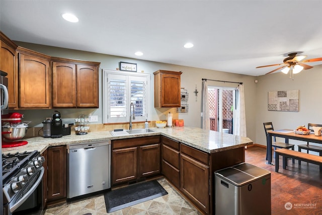 kitchen with kitchen peninsula, sink, light stone countertops, light hardwood / wood-style floors, and stainless steel appliances