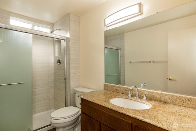 bathroom with vanity, a shower with door, and toilet