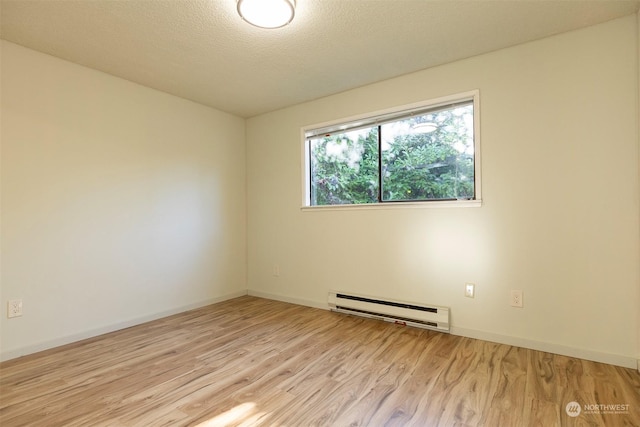 empty room featuring a textured ceiling, baseboard heating, and light hardwood / wood-style floors