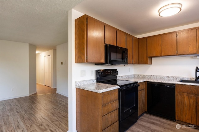 kitchen with sink, light hardwood / wood-style flooring, and black appliances