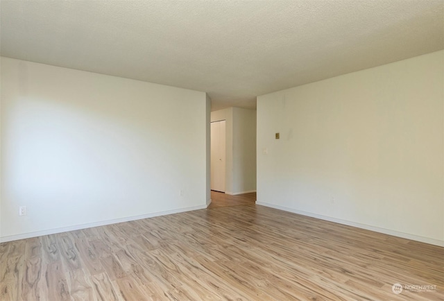 spare room featuring a textured ceiling and light hardwood / wood-style floors