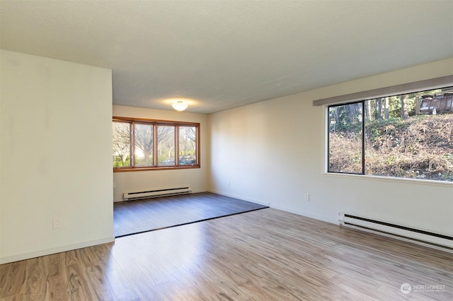 spare room featuring baseboard heating, a textured ceiling, and light wood-type flooring