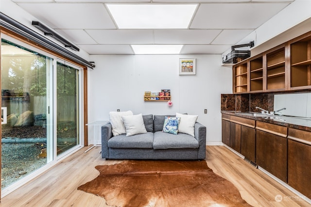 living area featuring plenty of natural light, light hardwood / wood-style flooring, and a paneled ceiling