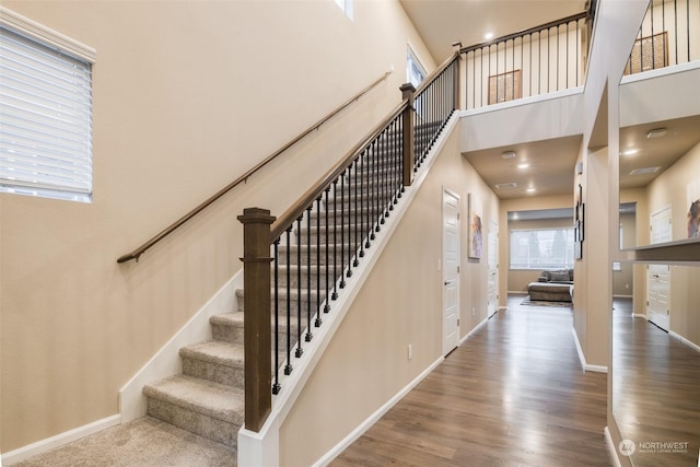 staircase featuring wood-type flooring and a towering ceiling