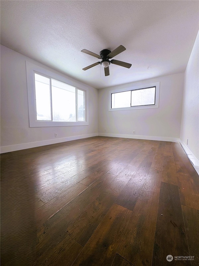 empty room with ceiling fan, dark hardwood / wood-style floors, and a textured ceiling