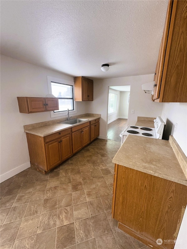 kitchen featuring a textured ceiling, sink, exhaust hood, and white range with electric stovetop