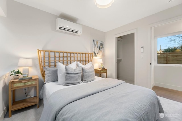 bedroom with a wall mounted air conditioner, a spacious closet, hardwood / wood-style floors, and a closet