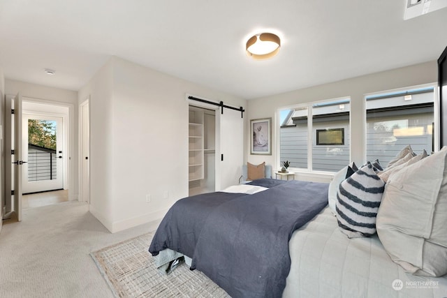 carpeted bedroom featuring a closet, a spacious closet, and a barn door