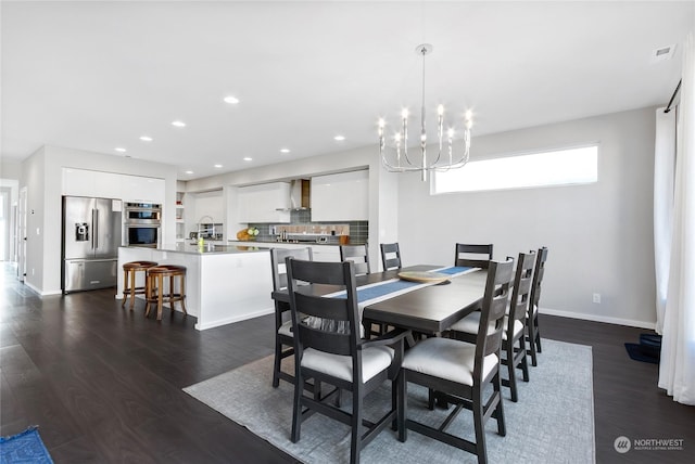 dining area with dark wood-type flooring, sink, and a chandelier