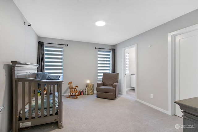 bedroom featuring a crib, multiple windows, light colored carpet, and connected bathroom