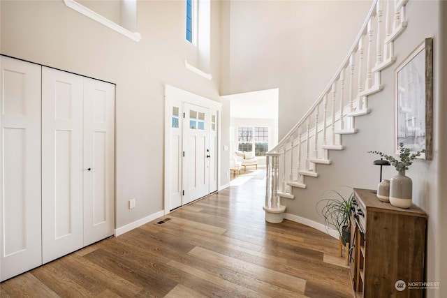 entrance foyer featuring a towering ceiling and wood-type flooring