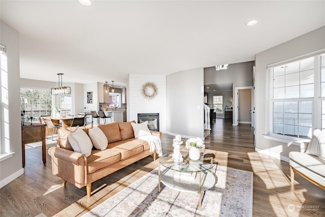 living room featuring an inviting chandelier, a large fireplace, sink, and dark hardwood / wood-style flooring