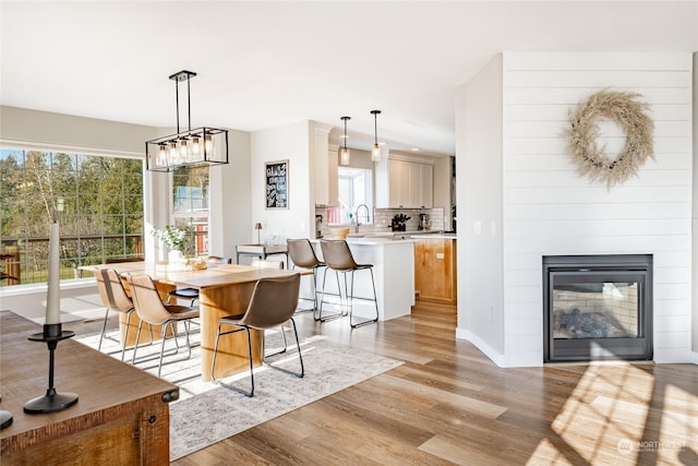 dining space featuring a fireplace, sink, and light wood-type flooring