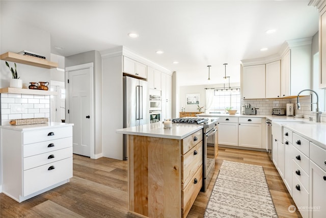 kitchen featuring sink, decorative light fixtures, appliances with stainless steel finishes, a kitchen island, and white cabinets