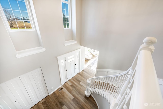 stairs featuring hardwood / wood-style flooring, a high ceiling, and a wealth of natural light