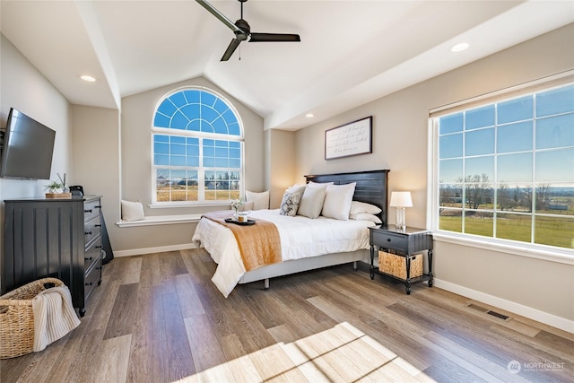 bedroom with multiple windows, lofted ceiling, and light hardwood / wood-style floors