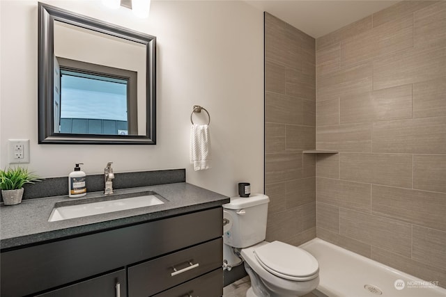 bathroom featuring vanity, toilet, and a tile shower