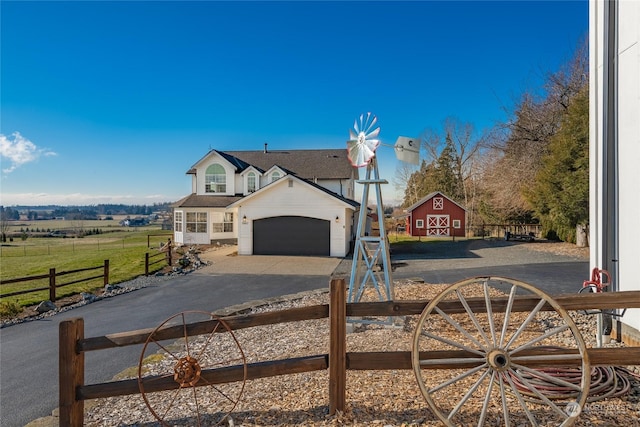 view of front of property featuring a garage and a rural view