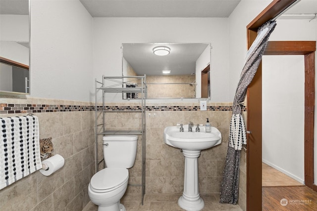 bathroom with hardwood / wood-style flooring, toilet, and tile walls