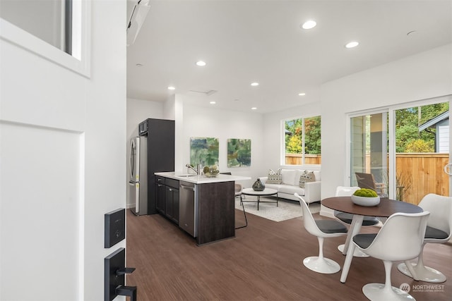 interior space featuring dark hardwood / wood-style flooring, plenty of natural light, stainless steel appliances, and an island with sink