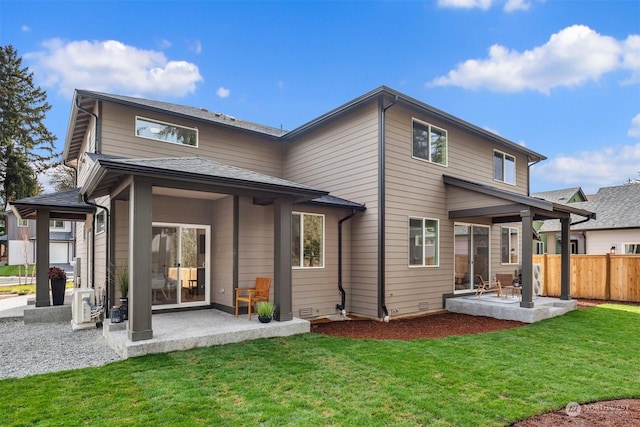 back of property with a patio area, a lawn, a shingled roof, and fence