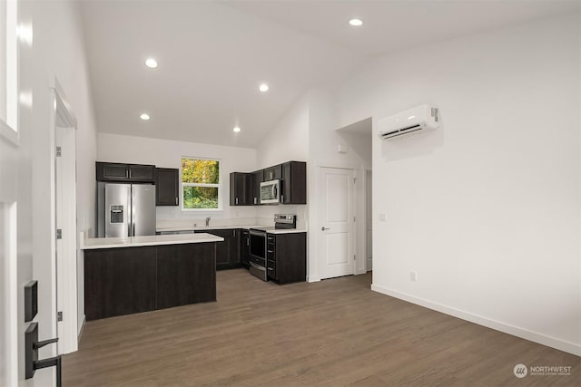 kitchen featuring an AC wall unit, wood finished floors, stainless steel appliances, light countertops, and baseboards