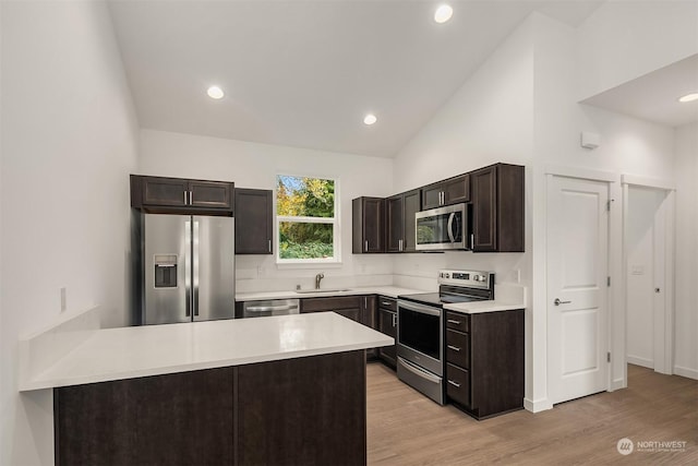 kitchen featuring sink, appliances with stainless steel finishes, dark brown cabinets, high vaulted ceiling, and light wood-type flooring