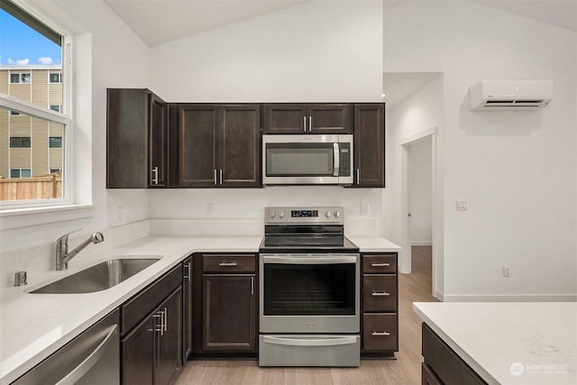 kitchen featuring a wall mounted air conditioner, stainless steel appliances, a sink, and vaulted ceiling