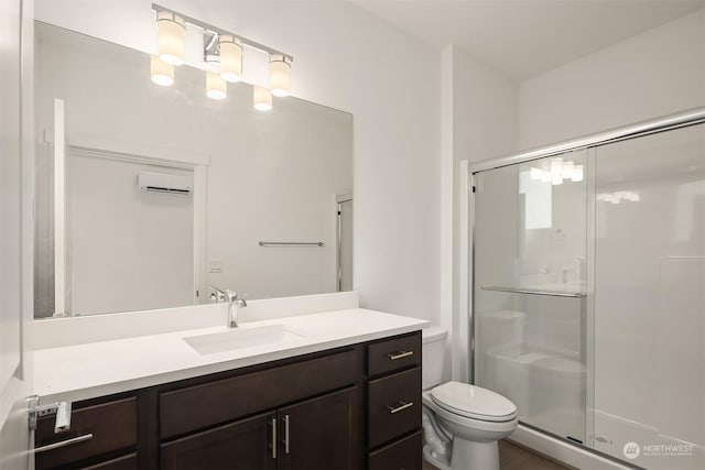 bathroom featuring vanity, a shower with shower door, a wall unit AC, and toilet