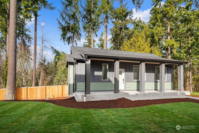 view of front of house with a front lawn, fence, board and batten siding, and a shingled roof