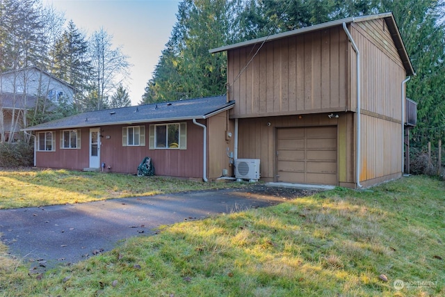 view of front of property with a garage, a front yard, and ac unit