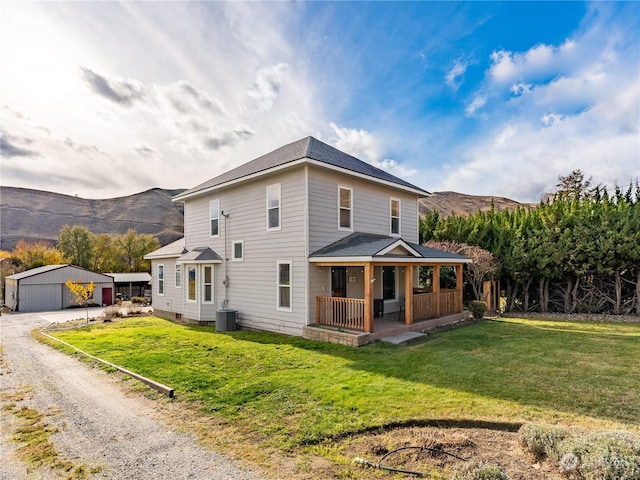 view of front of property with covered porch, a front yard, a garage, a mountain view, and an outdoor structure