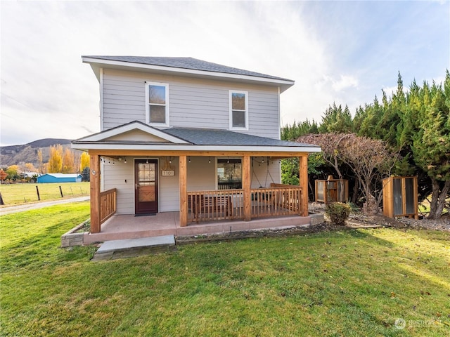 back of property featuring a porch, a mountain view, and a lawn