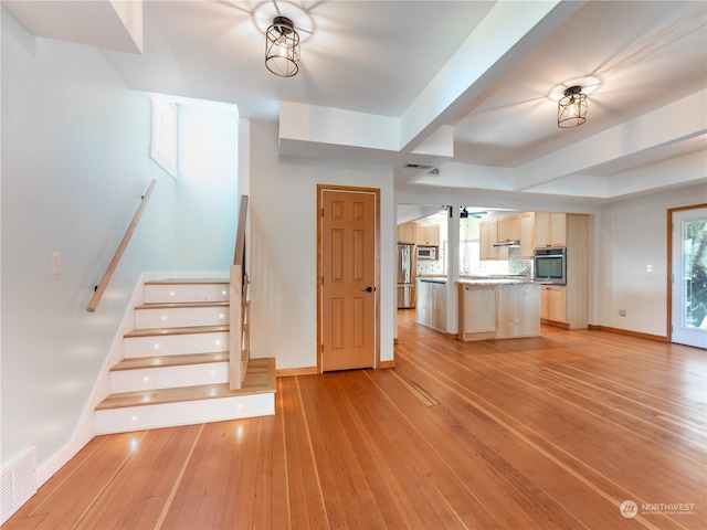 stairs with ceiling fan, a healthy amount of sunlight, and hardwood / wood-style floors