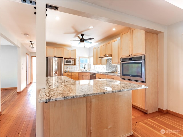 kitchen with light brown cabinetry, sink, tasteful backsplash, light stone countertops, and stainless steel appliances