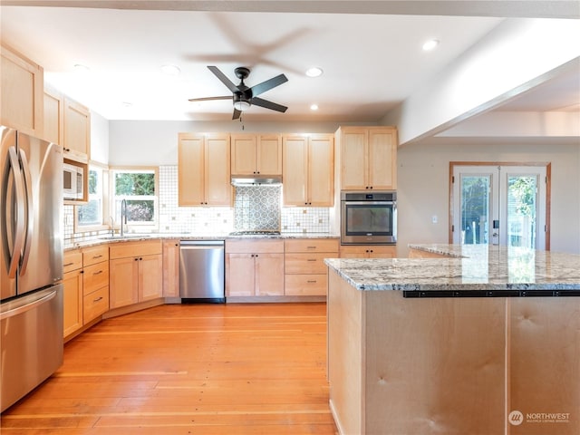 kitchen with light brown cabinetry, light stone countertops, sink, and stainless steel appliances