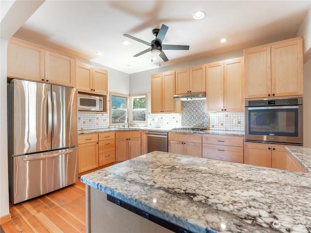 kitchen with light brown cabinetry, light stone countertops, light hardwood / wood-style flooring, and stainless steel appliances