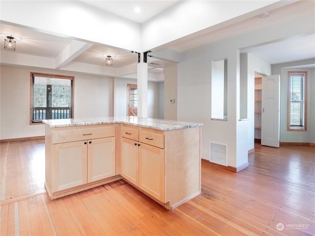 kitchen with a kitchen island, light hardwood / wood-style flooring, and light stone counters