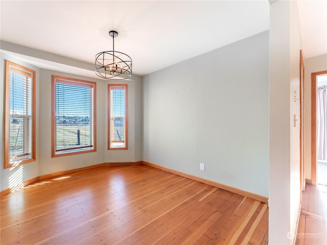 spare room featuring light hardwood / wood-style flooring and an inviting chandelier