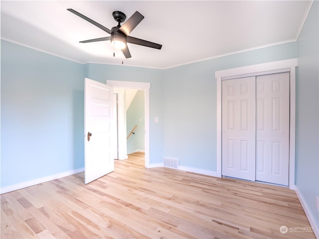 unfurnished bedroom with ceiling fan, a closet, crown molding, and light wood-type flooring