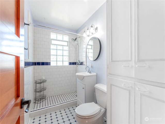 bathroom with tiled shower, vanity, and toilet