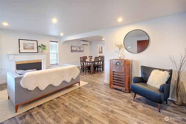 living room featuring hardwood / wood-style flooring and an AC wall unit