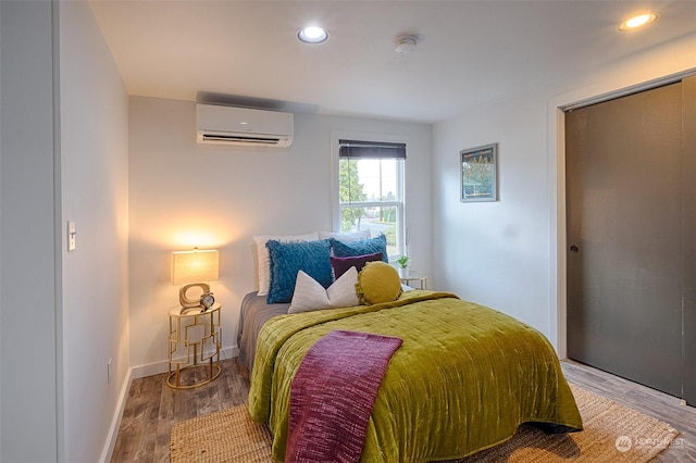 bedroom featuring hardwood / wood-style floors and a wall unit AC