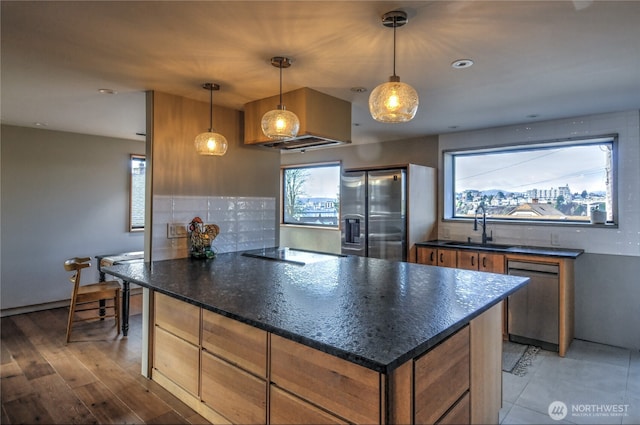 kitchen featuring stainless steel appliances, sink, hanging light fixtures, a healthy amount of sunlight, and backsplash