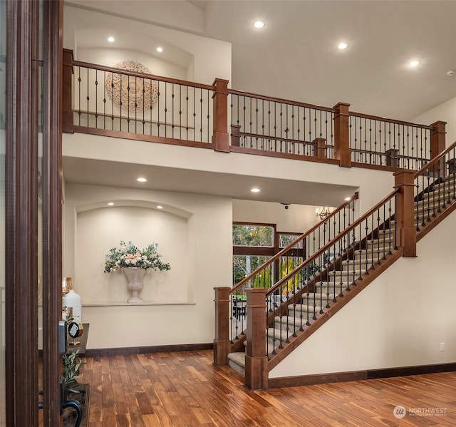 stairway with a high ceiling and wood-type flooring