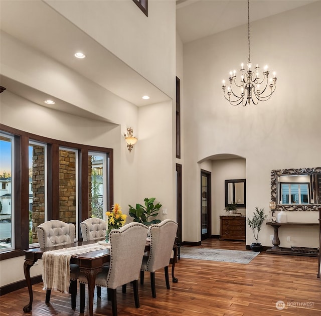 dining area featuring hardwood / wood-style flooring, a high ceiling, and an inviting chandelier