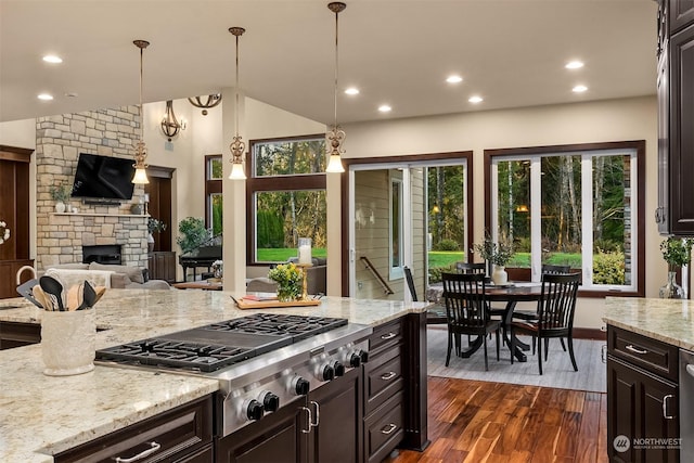 kitchen with light stone counters, hanging light fixtures, lofted ceiling, and stainless steel gas cooktop