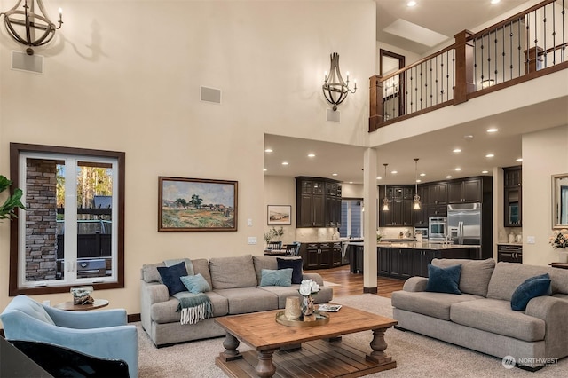 living room featuring light wood-type flooring, a towering ceiling, and a notable chandelier